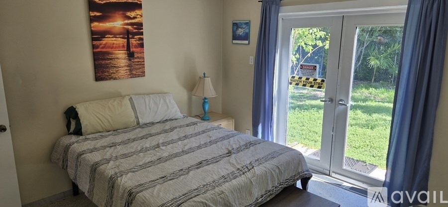 A bedroom with a large bed and a painting of a sunset on the wall.
