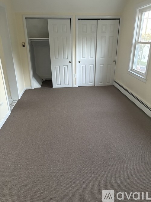 A room with carpeted floor and two white doors.