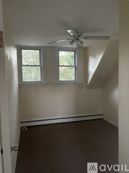 A room with a ceiling fan and two windows.