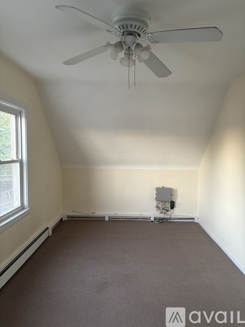 A room with a ceiling fan and a window.