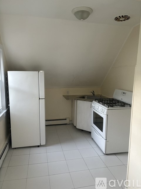 A white kitchen with a refrigerator, oven, and stove.