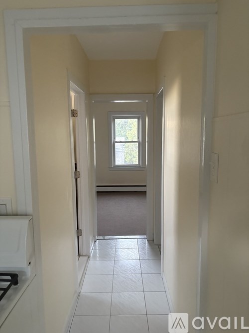 A hallway with a window and tiled floor.
