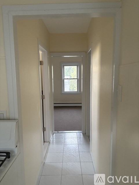A hallway with a window and tiled floor.