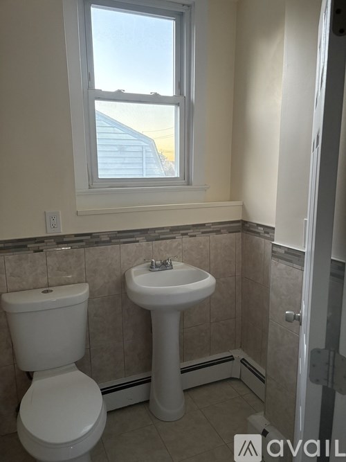 A bathroom with a toilet, sink, and window.