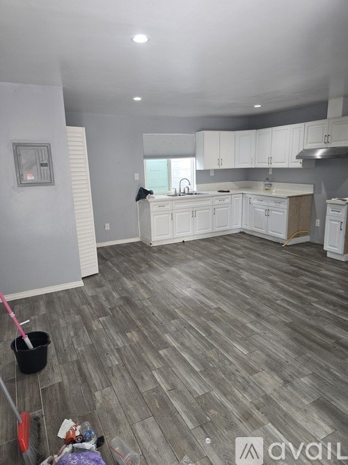 A kitchen with white cabinets and a grey floor.