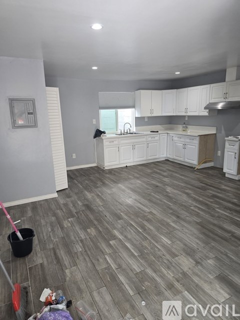A kitchen with white cabinets and a grey floor.