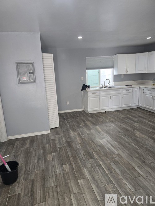 A room with wooden flooring and white cabinets.