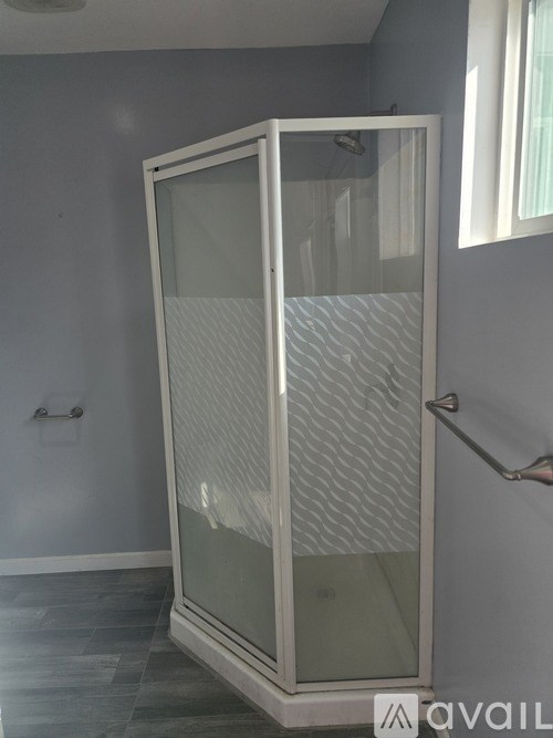 A glass shower enclosure with a white frame and a glass door.