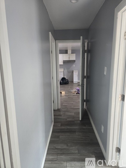 A hallway with a person sitting on the floor.