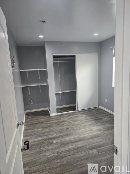 A room with a white door and a white wall with a shelf and a cupboard.