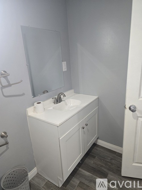 A white bathroom vanity with a sink and mirror.