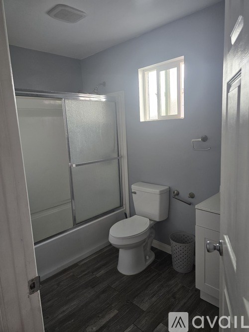 A bathroom with a toilet, a shower with a glass door, and a window.
