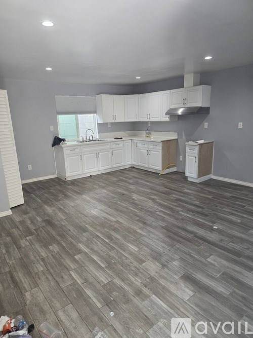 A kitchen with white cabinets and a wooden floor.