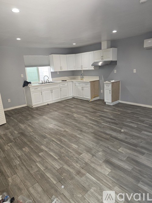A kitchen with white cabinets and a wooden floor.