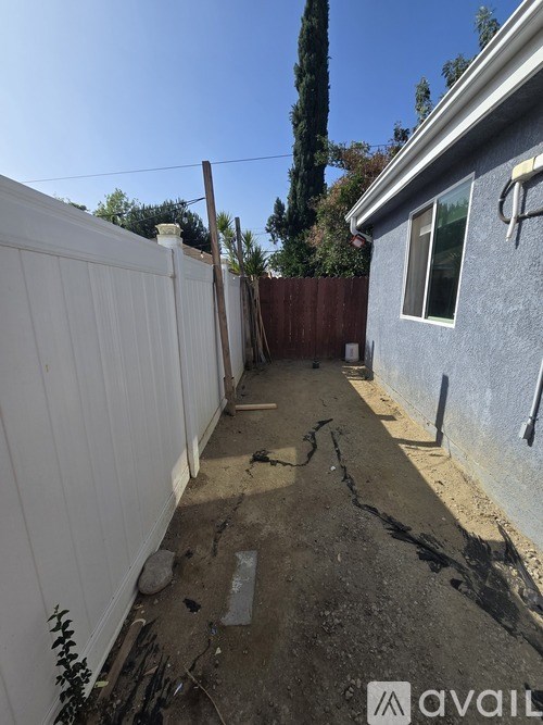 A backyard with a white fence and a blue house.