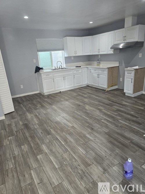 A kitchen with white cabinets and a wooden floor.