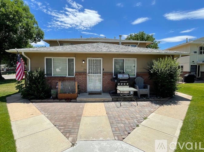 A house with a flag on the left and a patio with a table and chairs.
