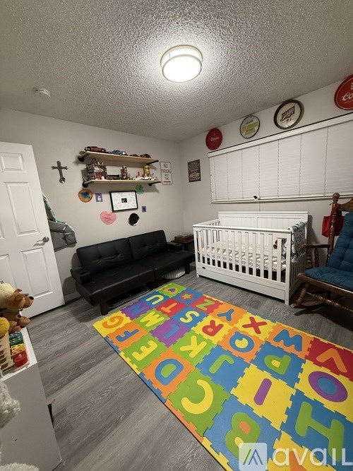 A baby's room with a white crib and a colorful alphabet rug.
