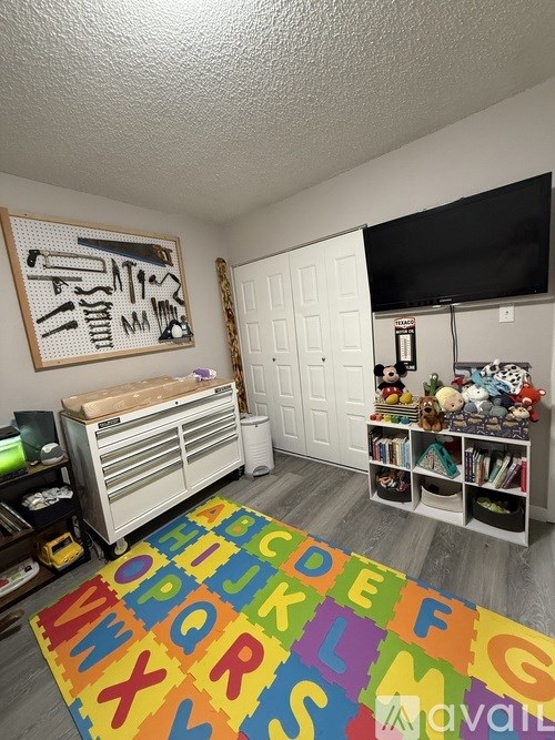 A room with a white door, a white dresser, a white bookcase, a white wall, a white ceiling, a white floor, a white rug, a white wall with a black border, a white wall with a black border,