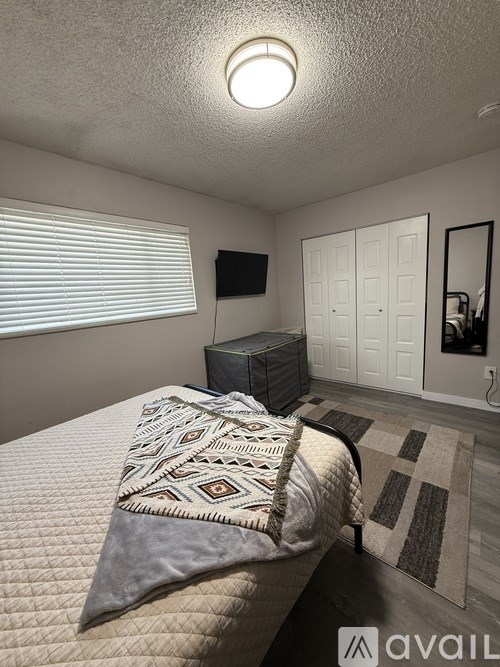 A bedroom with a bed and a TV mounted on the wall.