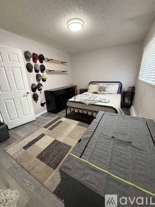 A bedroom with a bed, a rug, and a wall-mounted coat rack.