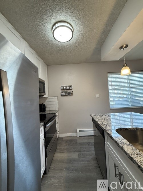 A kitchen with a refrigerator, microwave, and a window with blinds.
