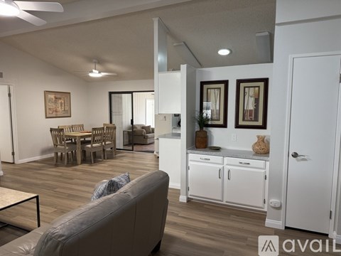 A living room with a grey couch and a dining table with chairs.