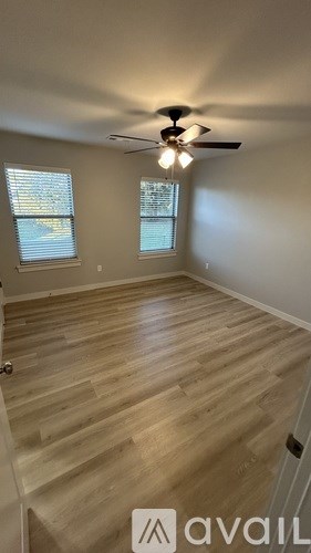 A room with a ceiling fan and wooden flooring.