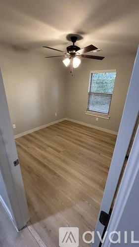 A room with a ceiling fan and a window with blinds.