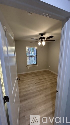A room with a ceiling fan and wooden flooring.