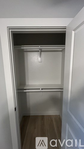 A small, empty closet with a white door and a wooden floor.