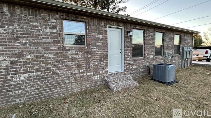 A brick house with a white door and a window with a reflection of a tree.