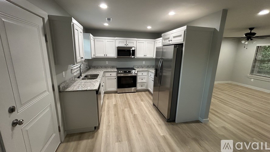 A modern kitchen with wooden floors and stainless steel appliances.