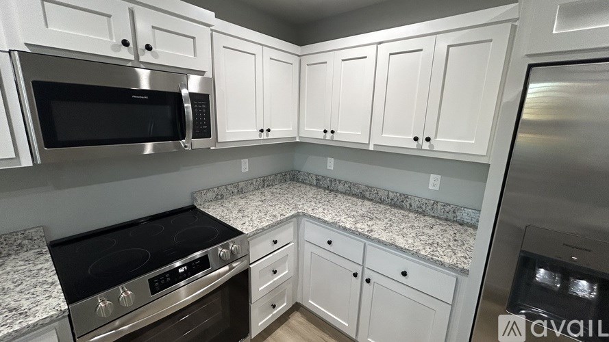 A kitchen with white cabinets and granite countertops.