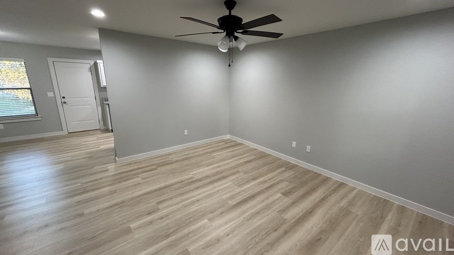 A room with a ceiling fan and wooden flooring.