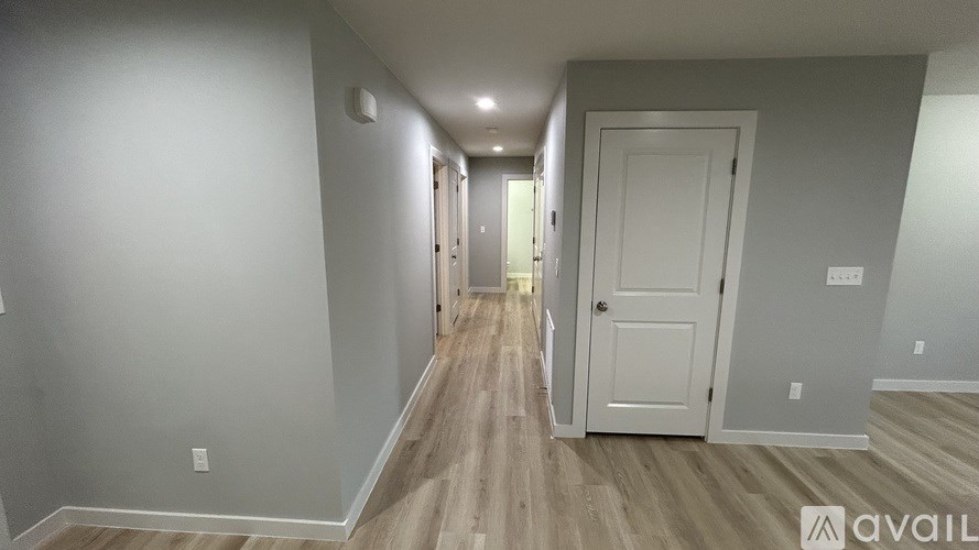 A long hallway with white doors and wood floors.