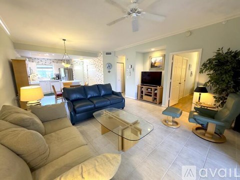 A living room with a blue couch and a glass coffee table.