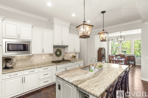 A kitchen with white cabinets and a marble countertop.
