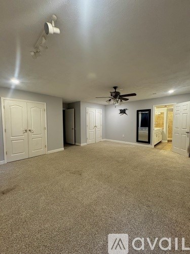 A room with a carpeted floor and a ceiling fan.