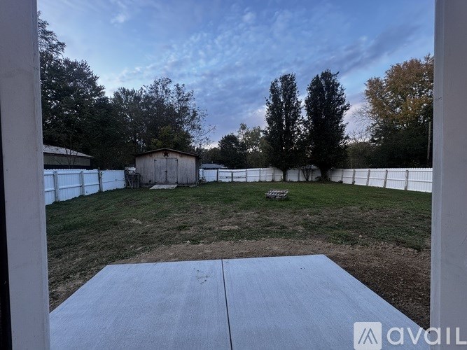 A backyard with a white fence and a shed.
