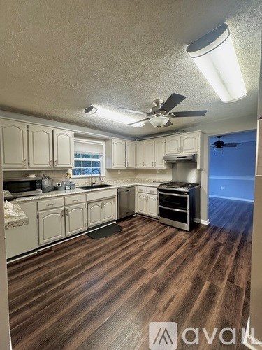 A kitchen with wooden floors and white cabinets.