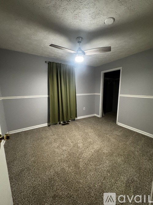 A room with a carpeted floor and a ceiling fan.