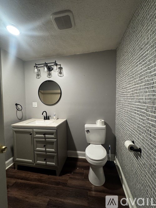A bathroom with a toilet, sink, and mirror.