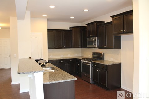 A kitchen with black cabinets and a granite counter top.