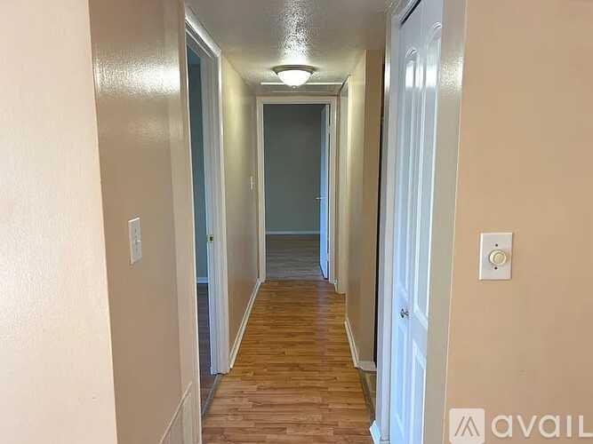 A long hallway with a light on the ceiling and a door at the end.