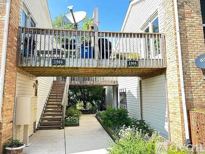 A balcony with a railing and a sign that says 1966 is surrounded by plants.