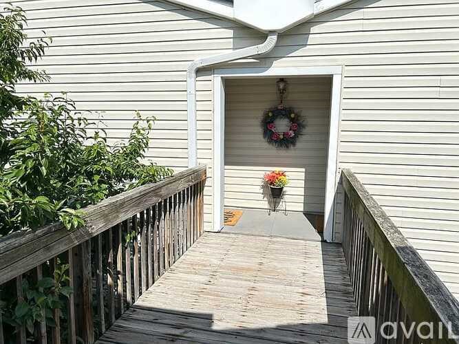 A wooden deck leads to a door with a wreath on it.