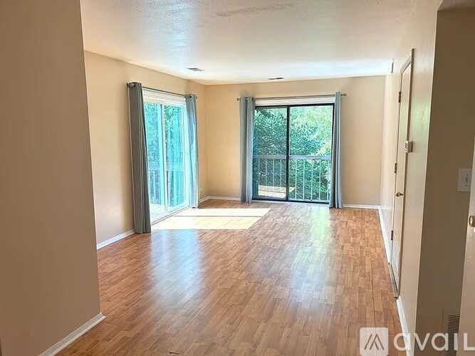 A room with wooden flooring and sliding glass doors leading to a balcony.