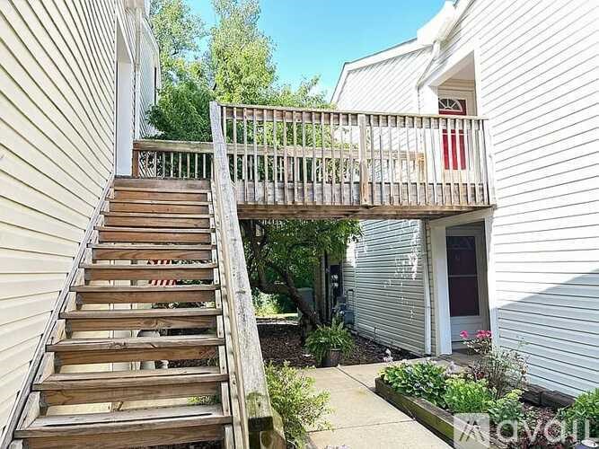 A wooden staircase leads to a balcony outside a house.