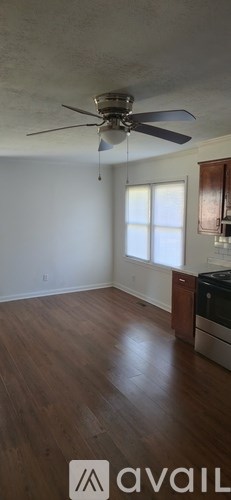 A room with a ceiling fan and wooden flooring.